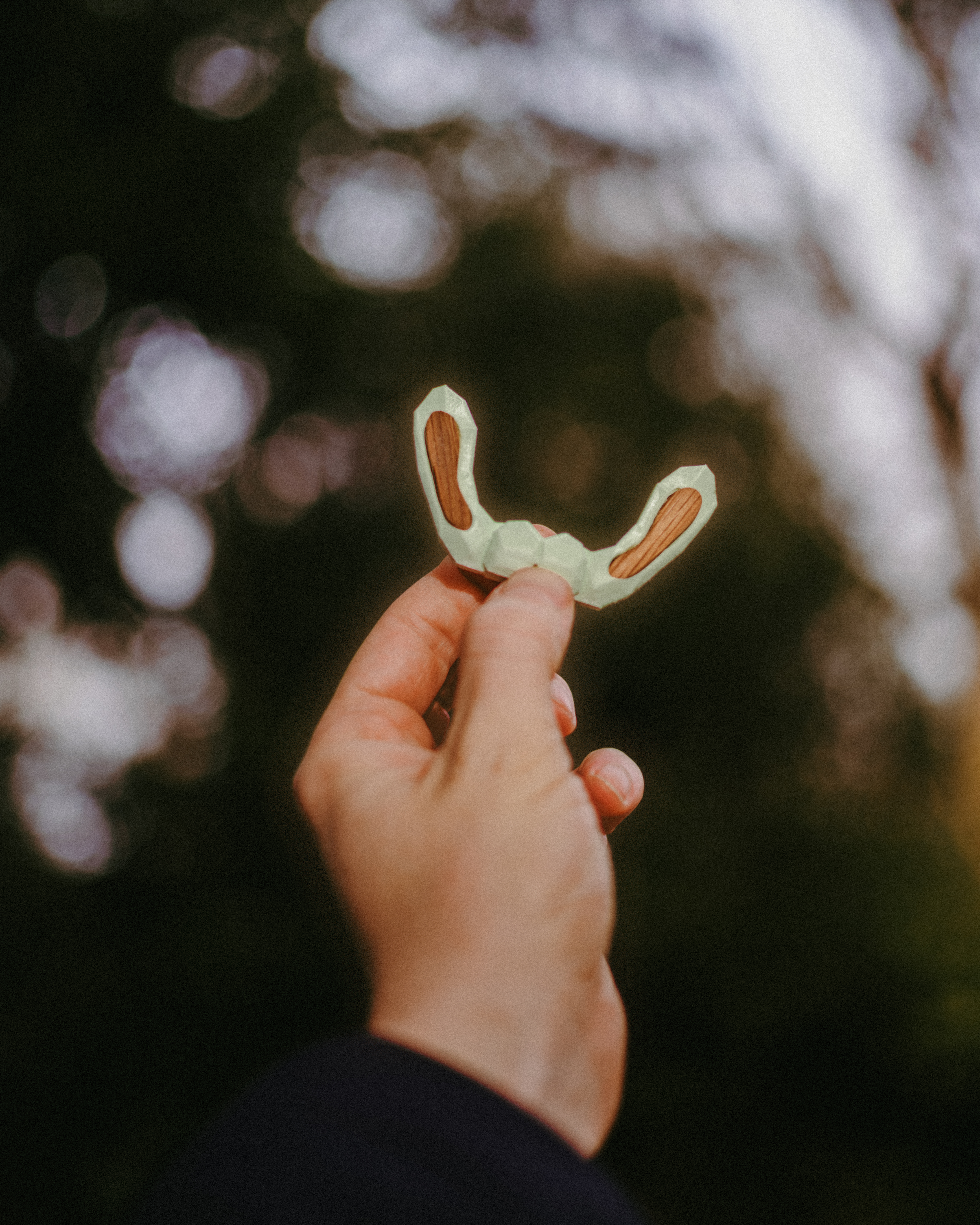A hand holds up a 3d-printed sycamore seed, wings inlaid with wood from the Sycamore Gap tree